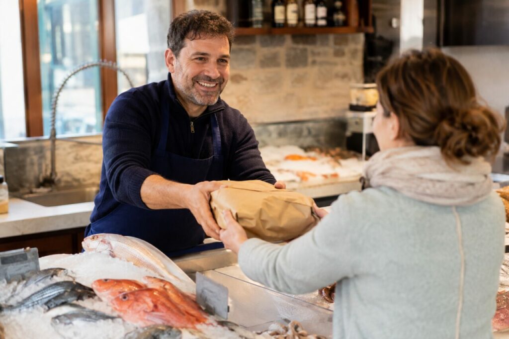 Échange entre poissonnier et cliente devant un étal de poissons