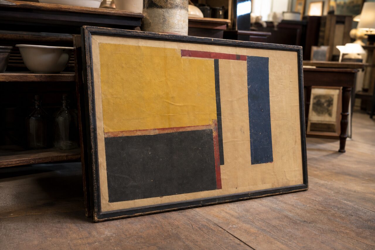 Weathered geometric poster viewed from the left on an antique-shop floor