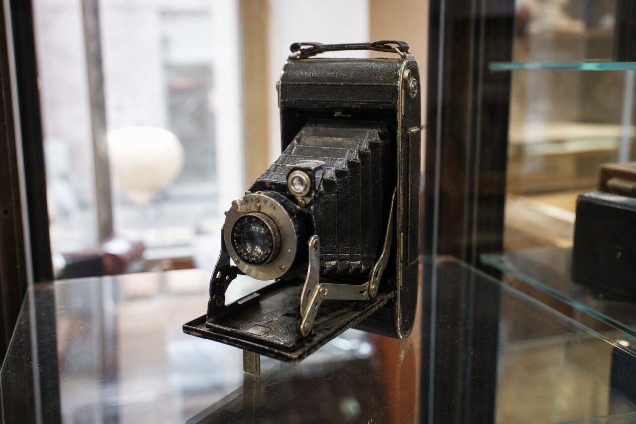 Black folding camera with extended bellows in a display case