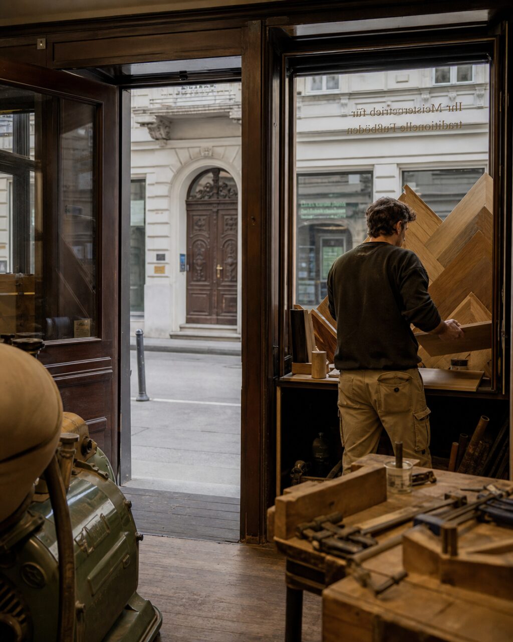 Handwerker mit Parkettmustern in der offenen Werkstatt eines Wiener Bodenladens