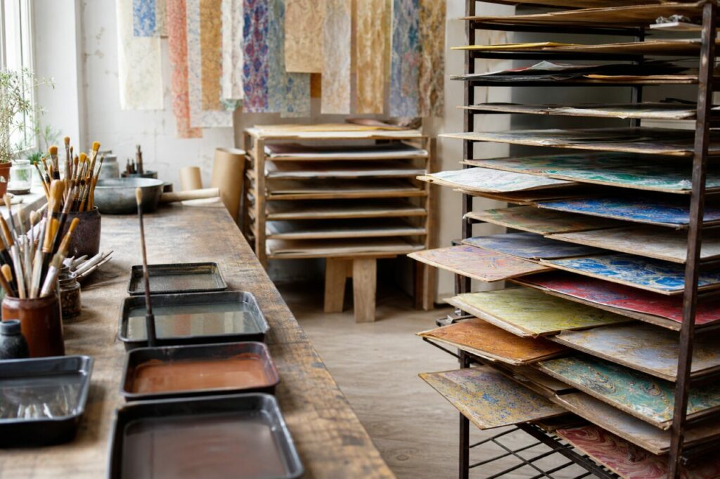 Atelier de papier marbré avec feuilles séchant sur des claies au-dessus de bains pigmentés
