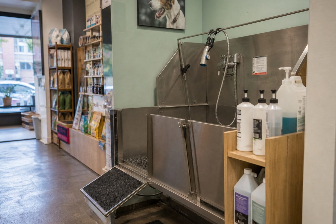 Hondenwasbad met sproeier en shampooflessen op een rij