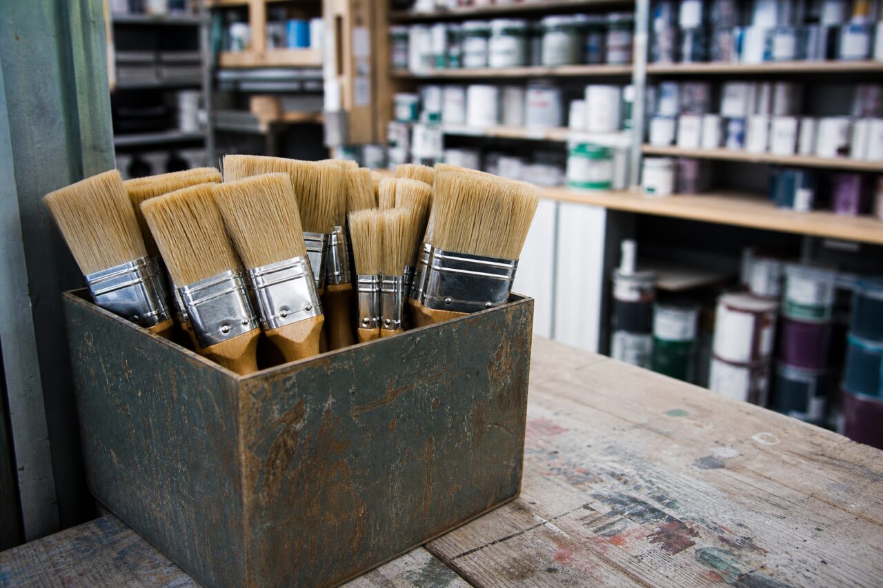 Brush holder on a workbench before shelves of cans