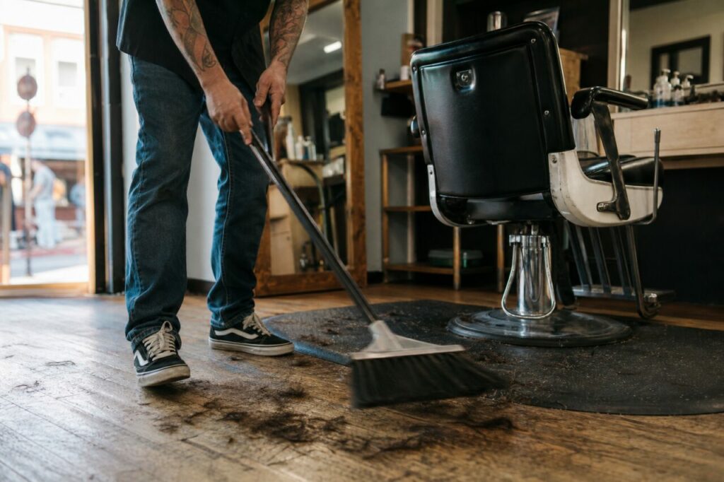 Balai entre un fauteuil noir et des mèches au sol