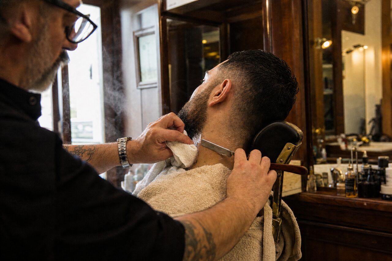 Barbier penché sur une nuque dans un salon boisé