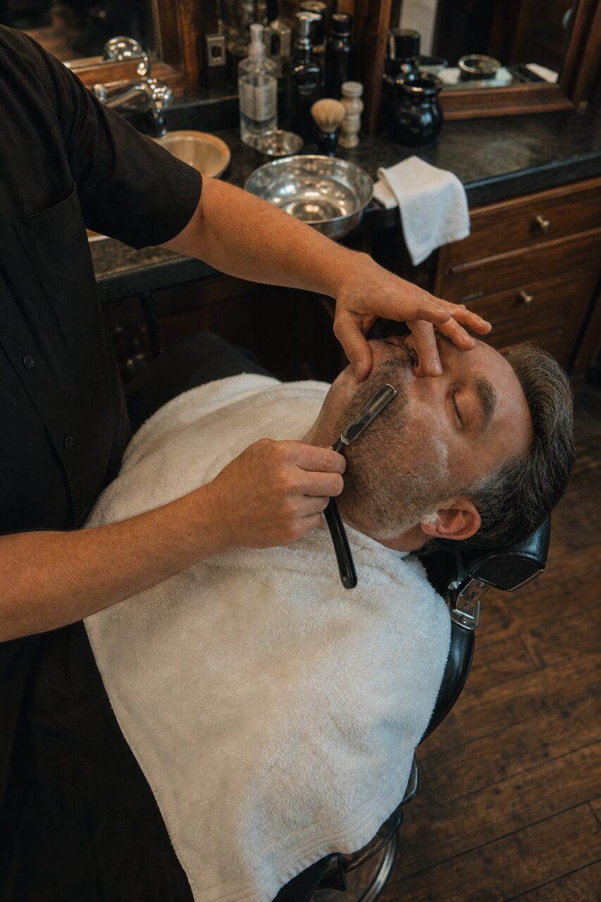 Barbier bereidt een scheerbeurt met open mes in de zaak voor