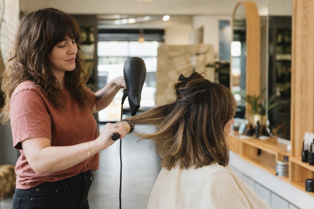 Föhnen von braunem Haar mit hellen Strähnen