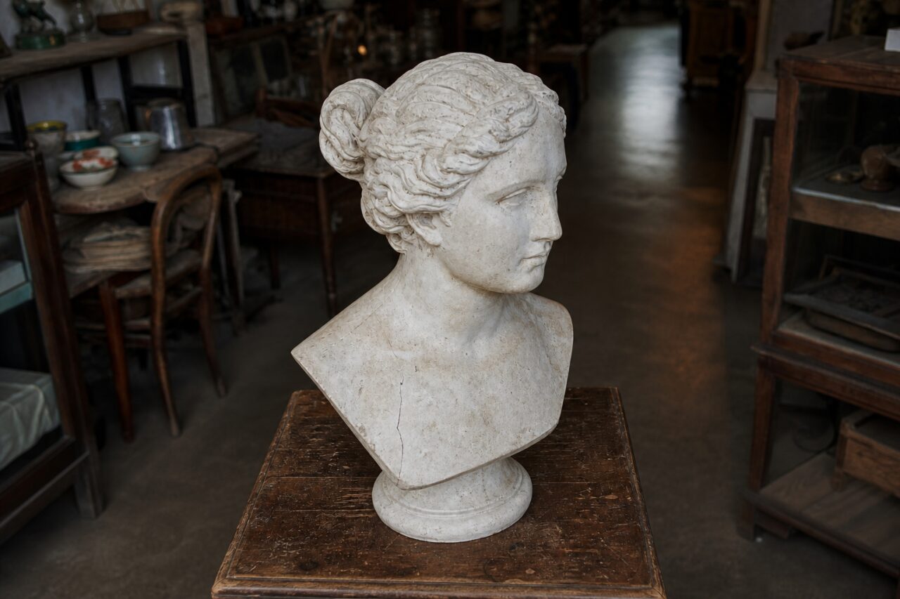 Slight overhead view of a light plaster bust on a vintage cabinet