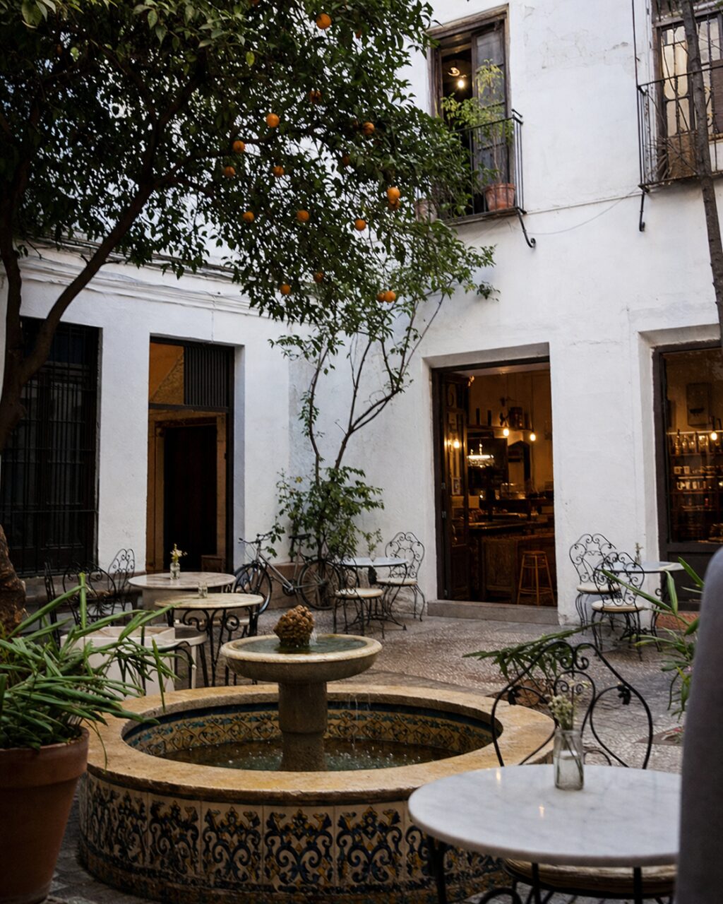 Caféhof mit Tischen rund um einen gefliesten Brunnen