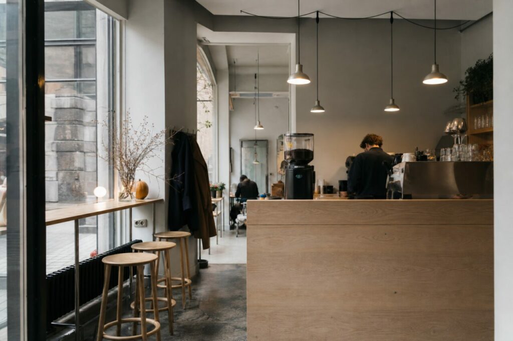 Café minimaliste avec comptoir en bois clair et grandes baies