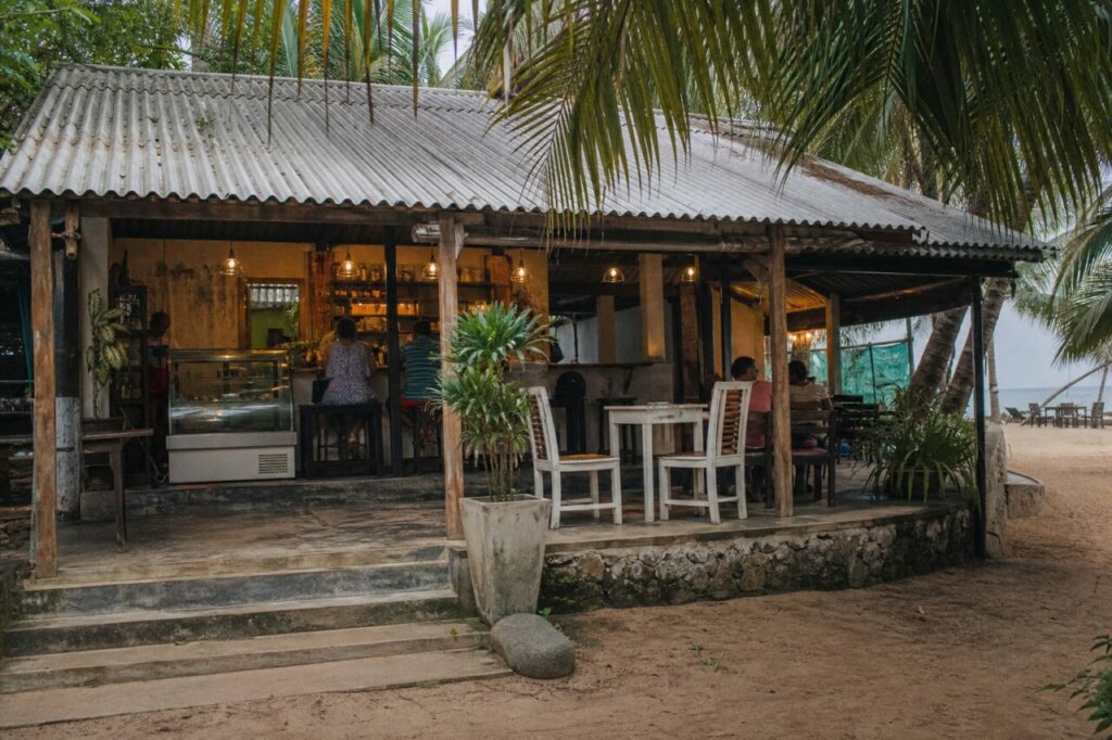 Café ouvert sous les palmiers au bord du sable