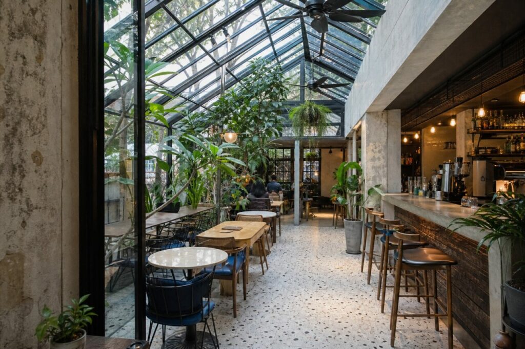 Café sous verrière avec comptoir en béton et feuillage