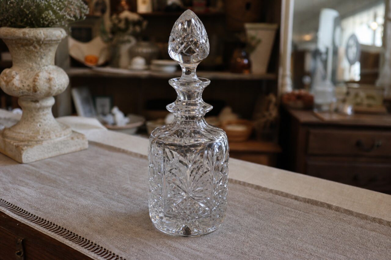 Carafe en cristal taillé avec bouchon à facettes sur une table ancienne