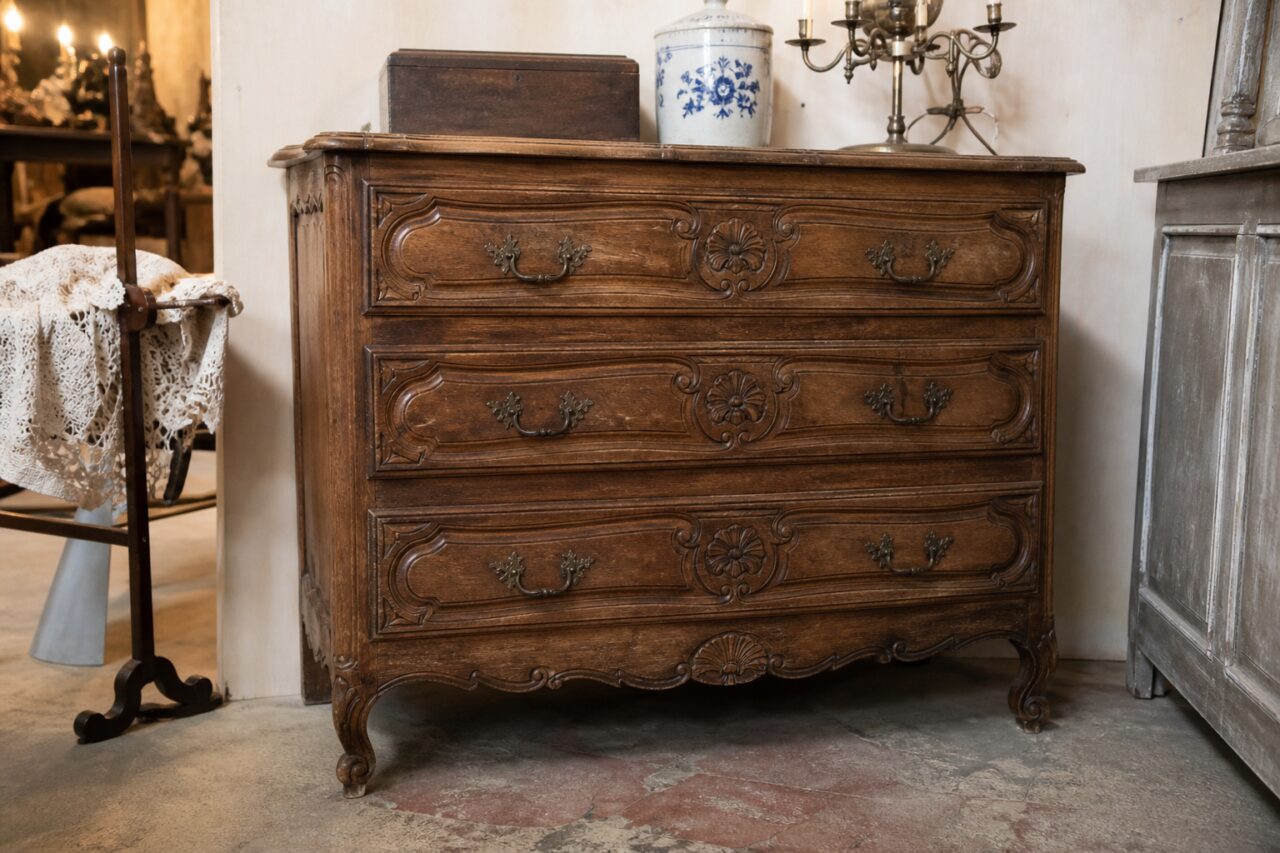 Carved wooden antique chest of drawers with three drawers in a vintage shop