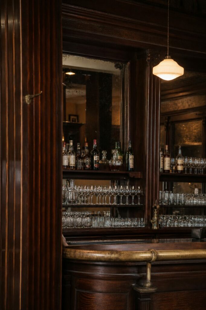 Curved counter facing a mirror, bottles and aligned glassware