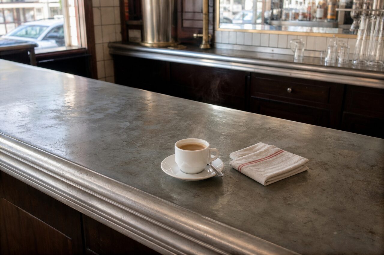 Comptoir en zinc avec café, serviette et verrerie derrière le bar