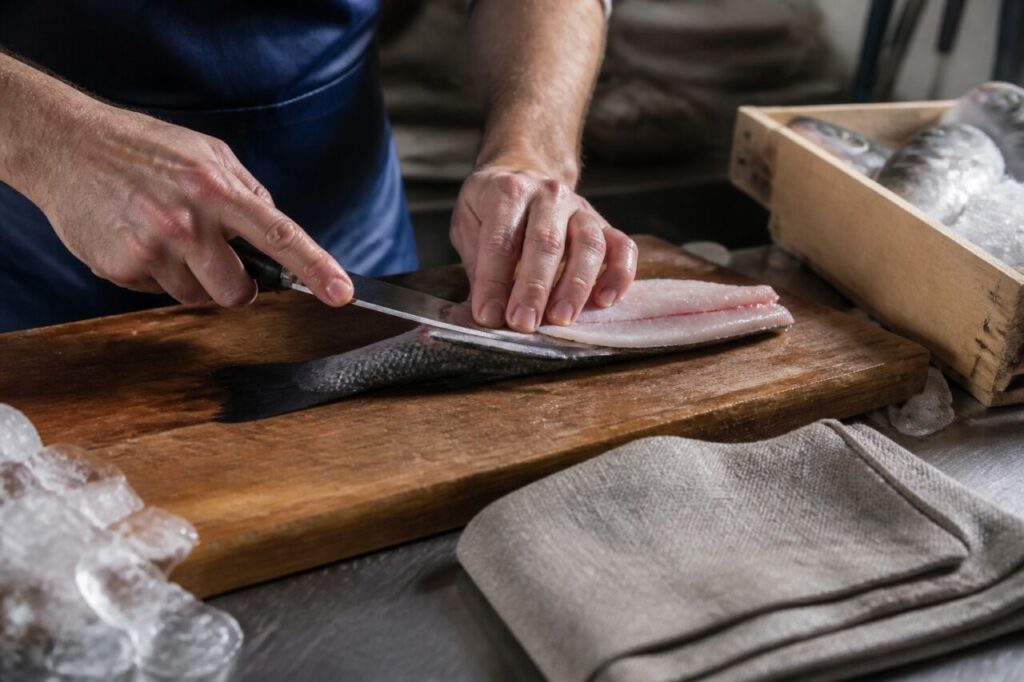 Découpe d’un filet de poisson sur une planche en bois à la poissonnerie