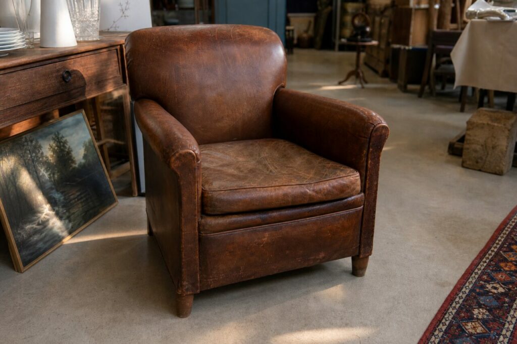 Détail du balancier doré derrière la vitre d’un fauteuil club en cuir brun