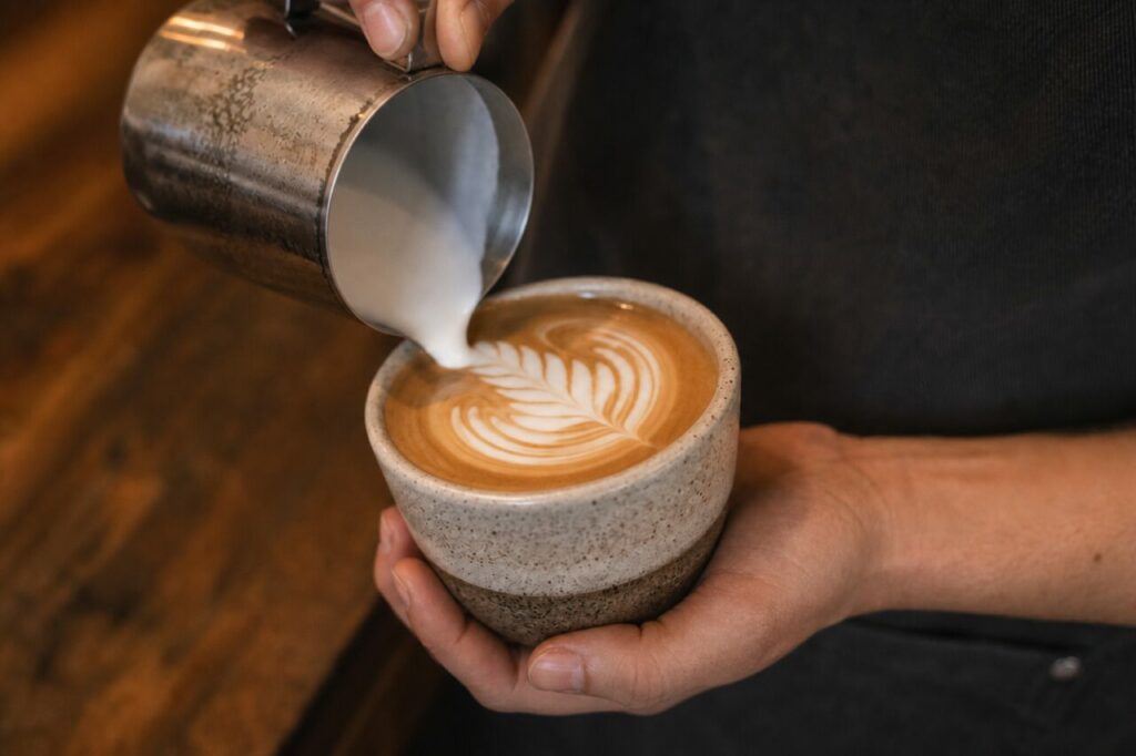 Een bladpatroon in een koffiekop met een melkkannetje