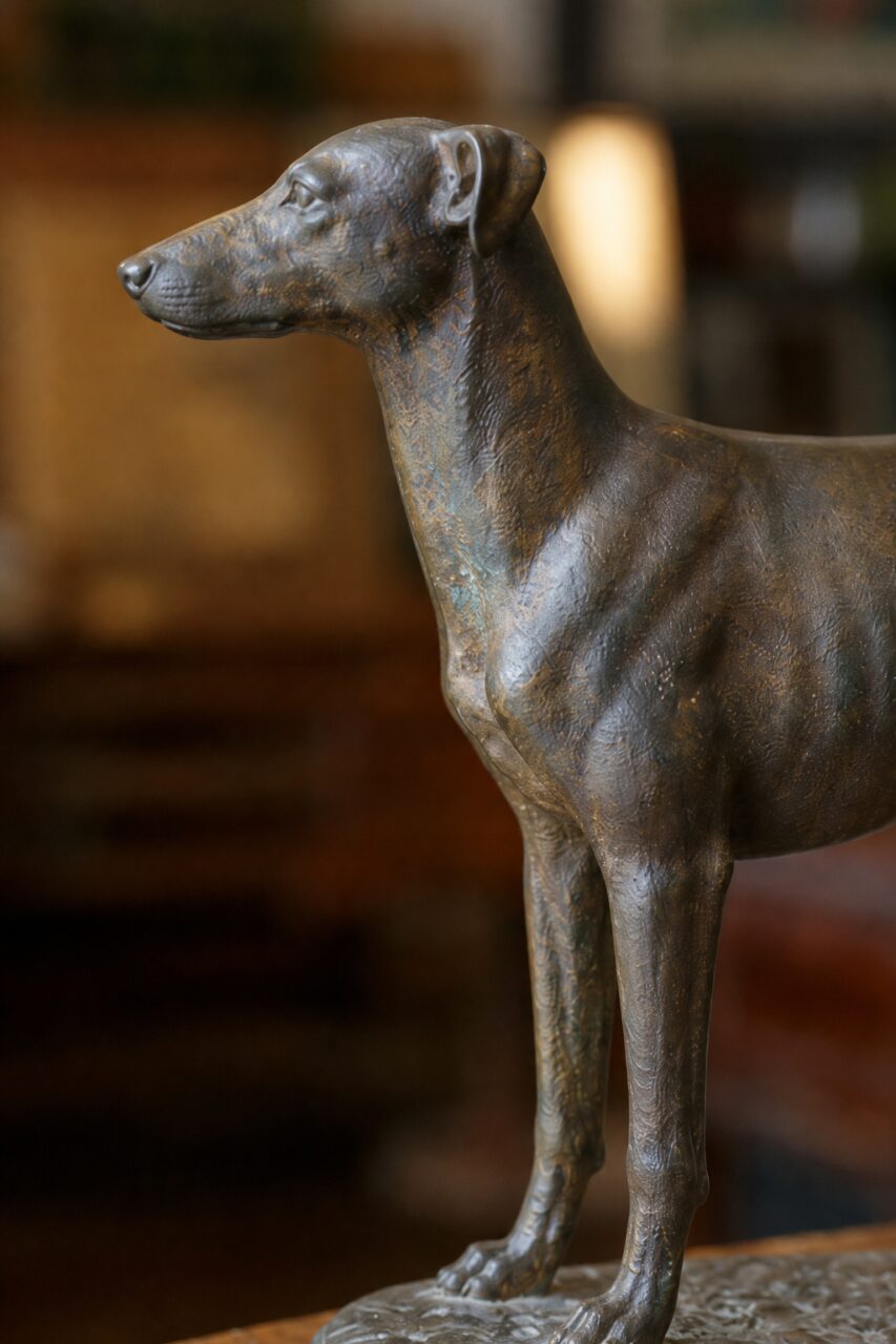 Vertical close-up of the head and chest of a bronze dog sculpture