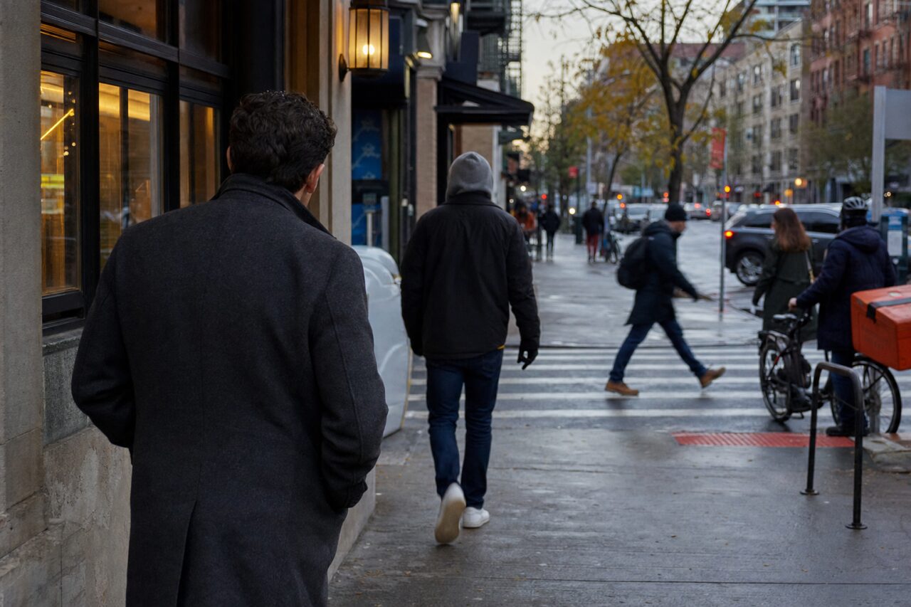 Deux hommes de dos sur un trottoir humide