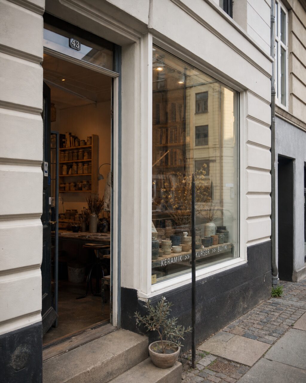 Hochformatige Fassade eines Kopenhagener Keramikateliers mit offener Tür und Schaufenster