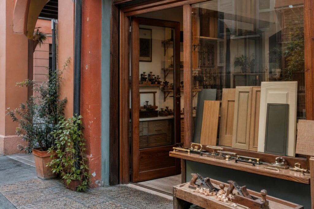 Fassade einer Tischlerwerkstatt mit Holzplatten und Hobeln unter Bologneser Arkaden