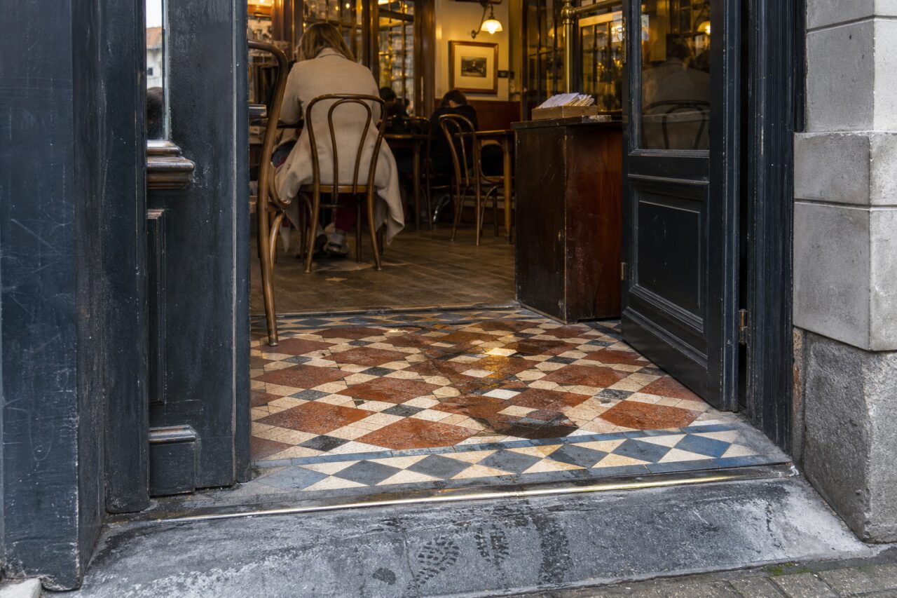 Entrée de brasserie ouverte sur un sol ancien en mosaïque