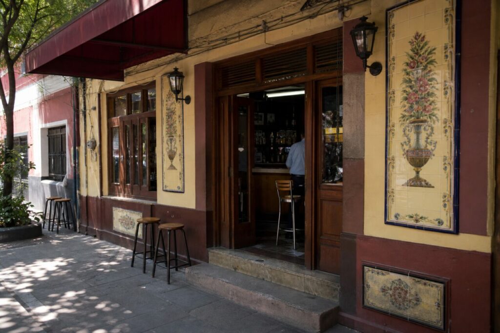 Façade jaune à panneaux floraux sous un auvent bordeaux