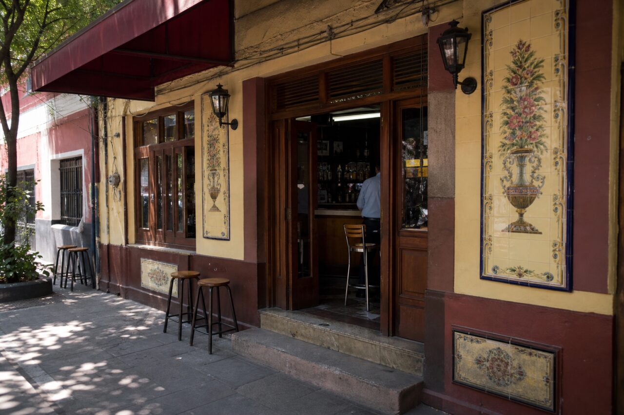 Façade jaune à panneaux floraux sous un auvent bordeaux