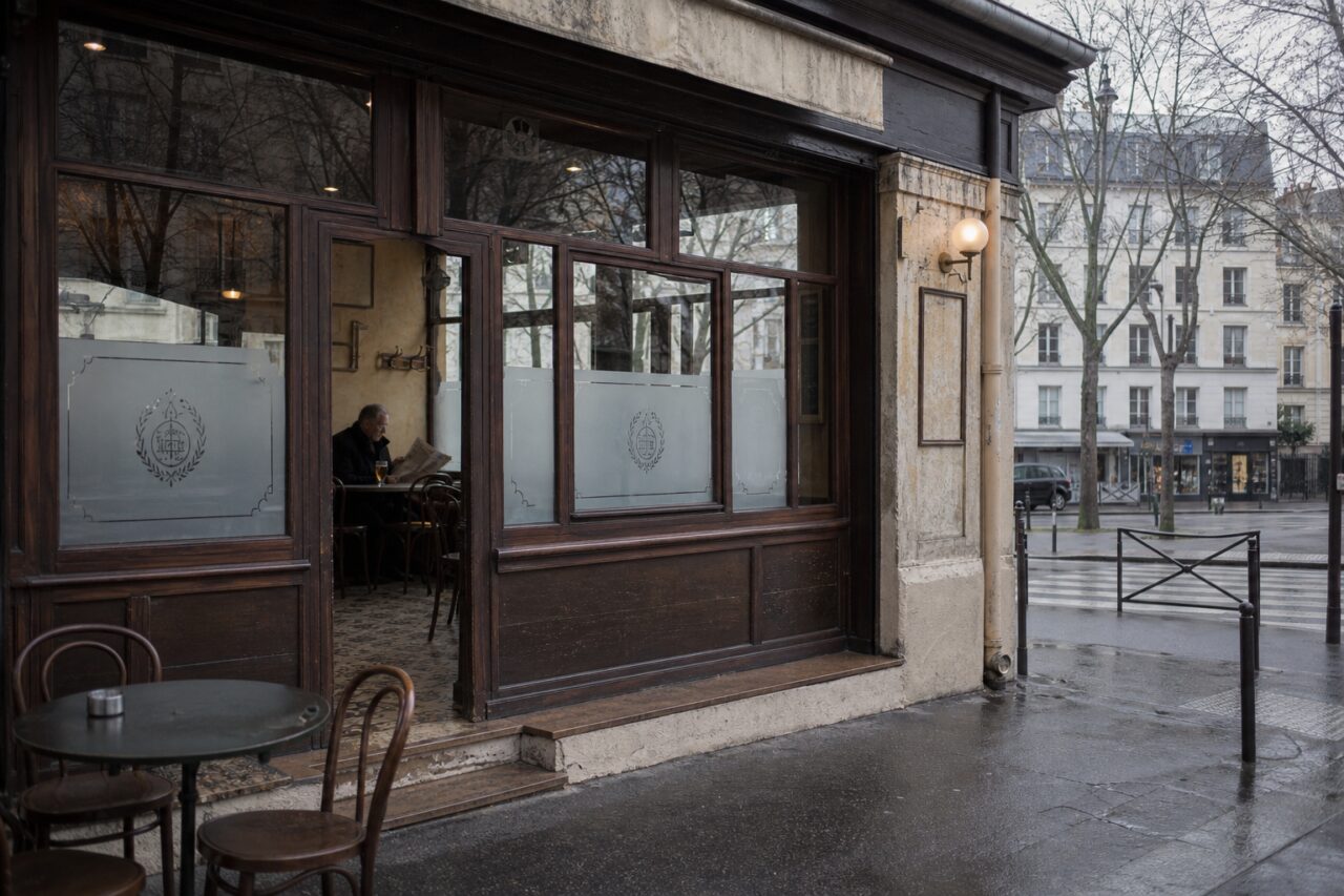 Façade vitrée sombre donnant sur un trottoir mouillé