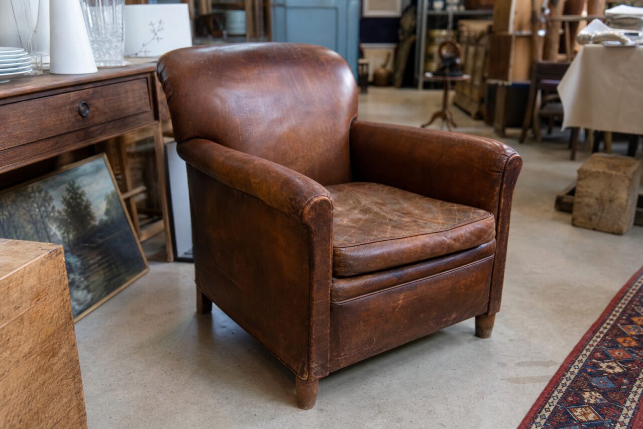 Patinated brown leather club chair with loose seat cushion in an antiques shop
