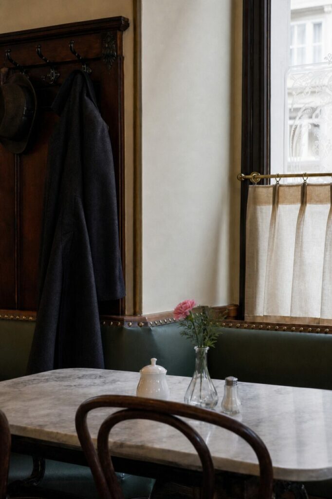 Fiore rosa davanti a panca verde e tendina della finestra