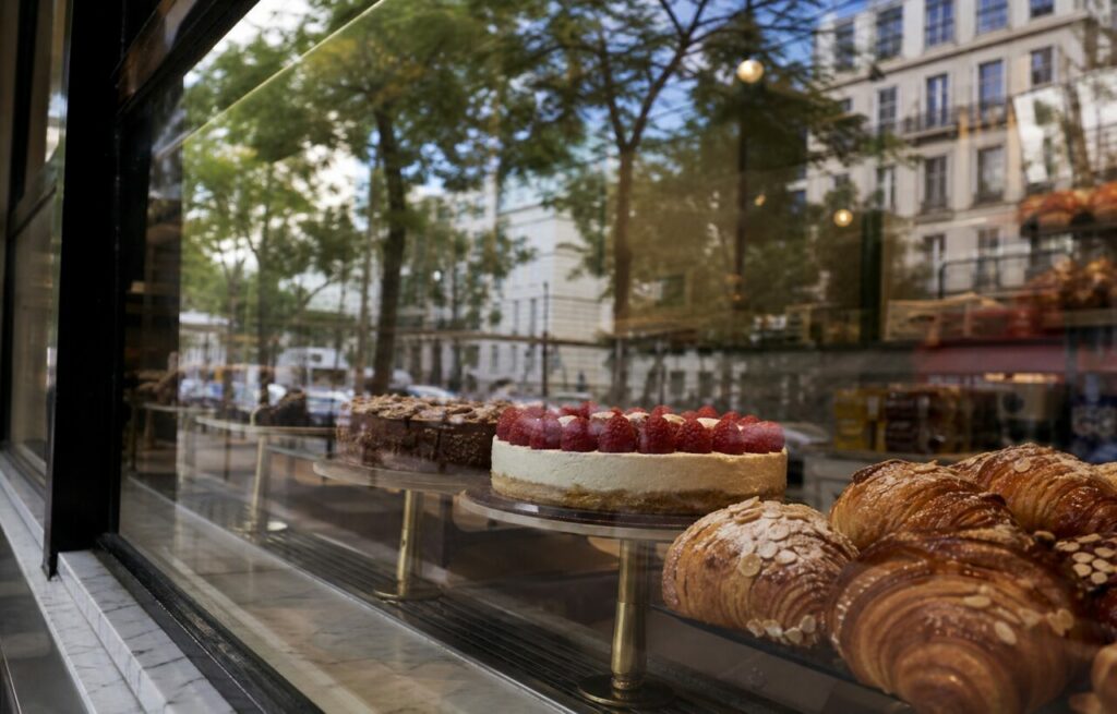 Gâteau aux framboises et viennoiseries derrière une vitrine réfléchissante