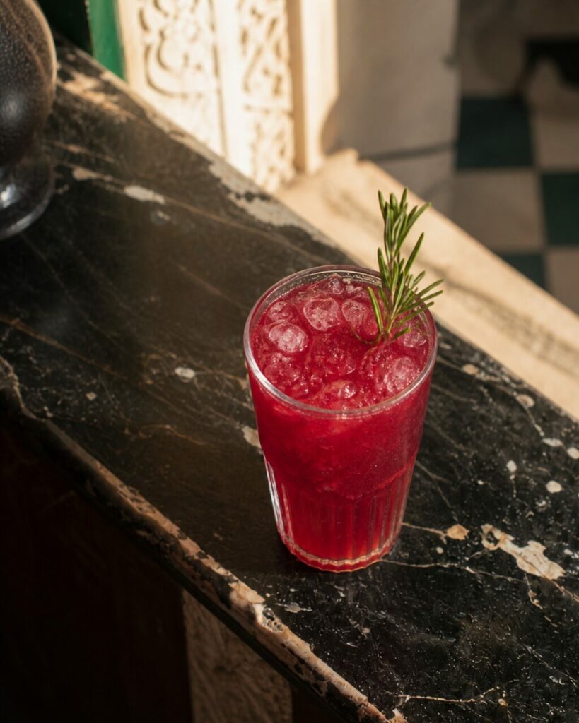 Ice and sprig seen above a glass filled with red liquid