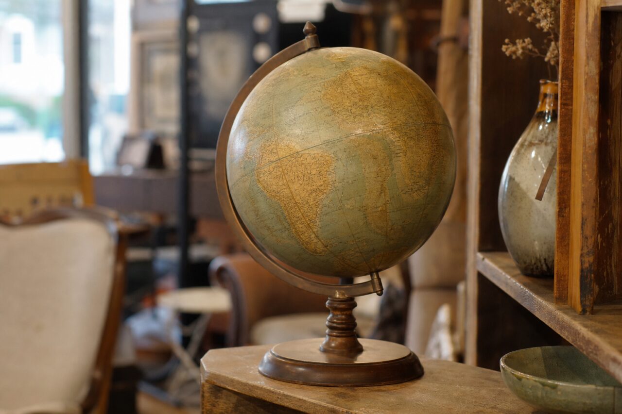 Globo terráqueo antiguo patinado sobre soporte de madera en una tienda de antigüedades