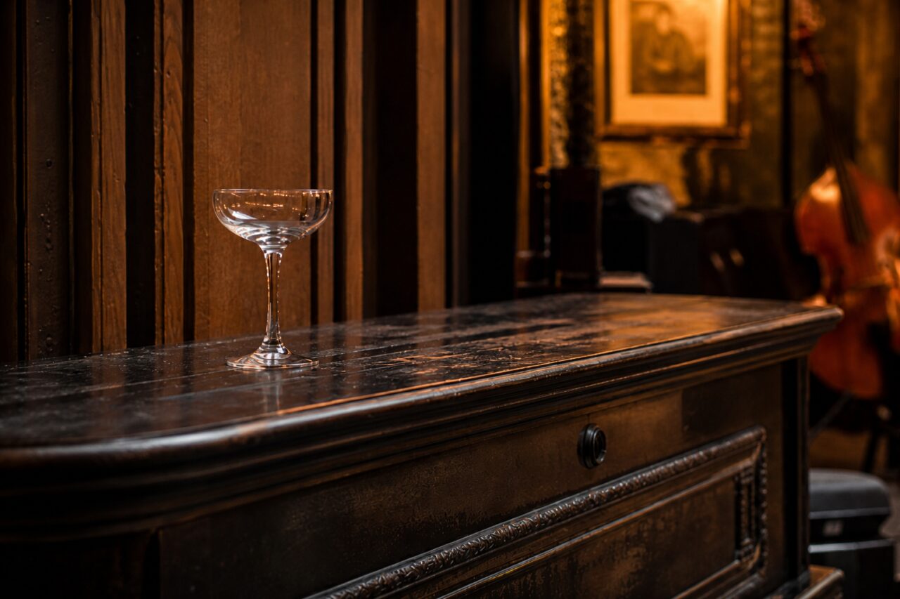 Primer plano de una copa sobre el piano negro de un bar musical