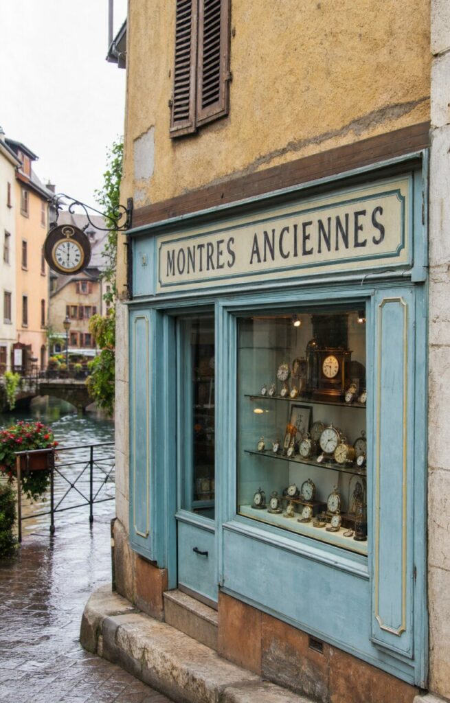 Horlogerie ancienne à Annecy, devanture bleu pastel et collection de montres en vitrine