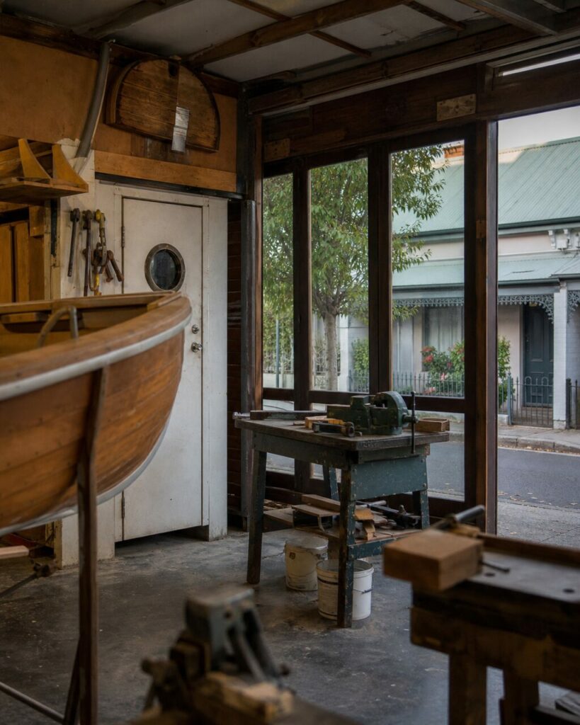 Intérieur d’un atelier de bateaux avec étau et coque devant les fenêtres