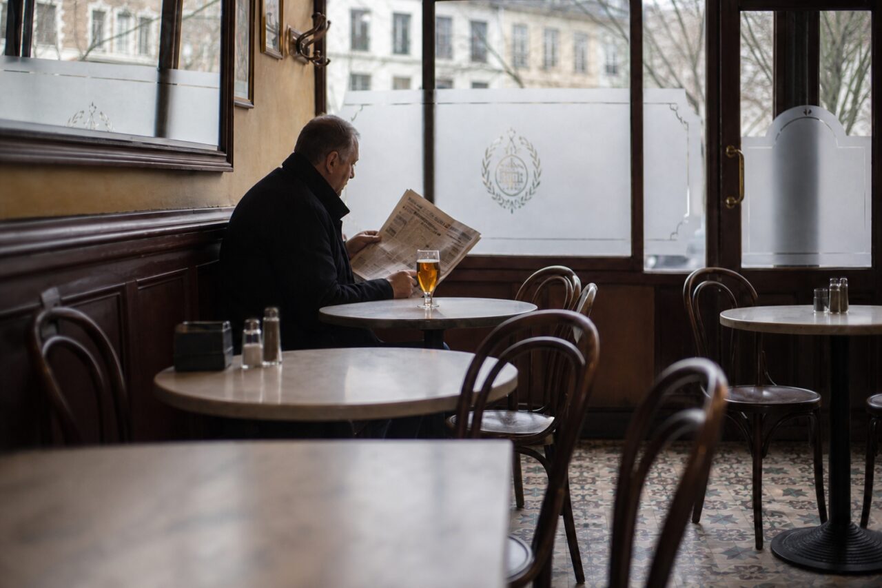 Offene Zeitung und bernsteinfarbenes Getränk vor Milchglasfeldern