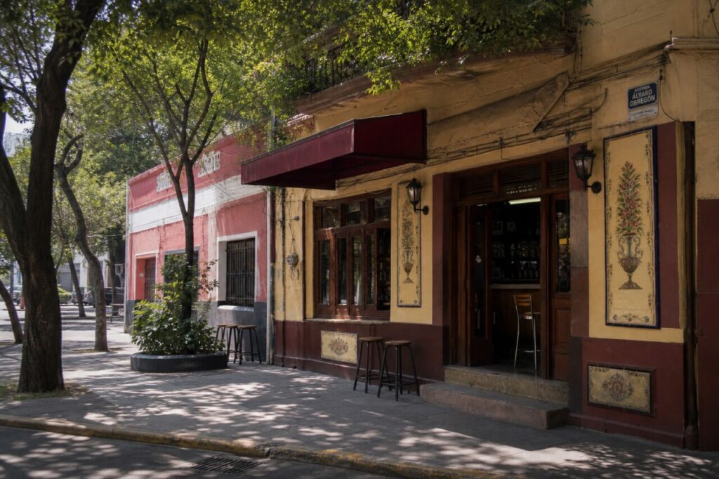Large trottoir arboré devant une façade à auvent bordeaux