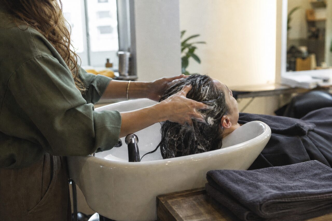 Haarwäsche mit Schaum in einem weißen Salonwaschbecken