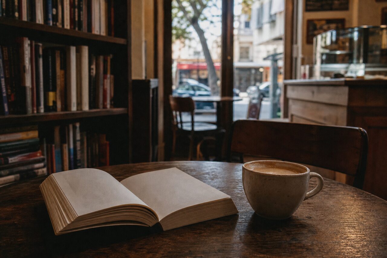 Open boek en lichte kop op een cafétafel