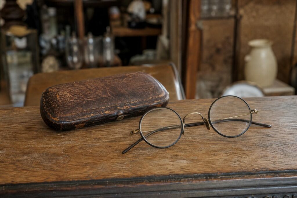 Alte runde Brille und abgenutztes Lederetui auf einem Holztisch