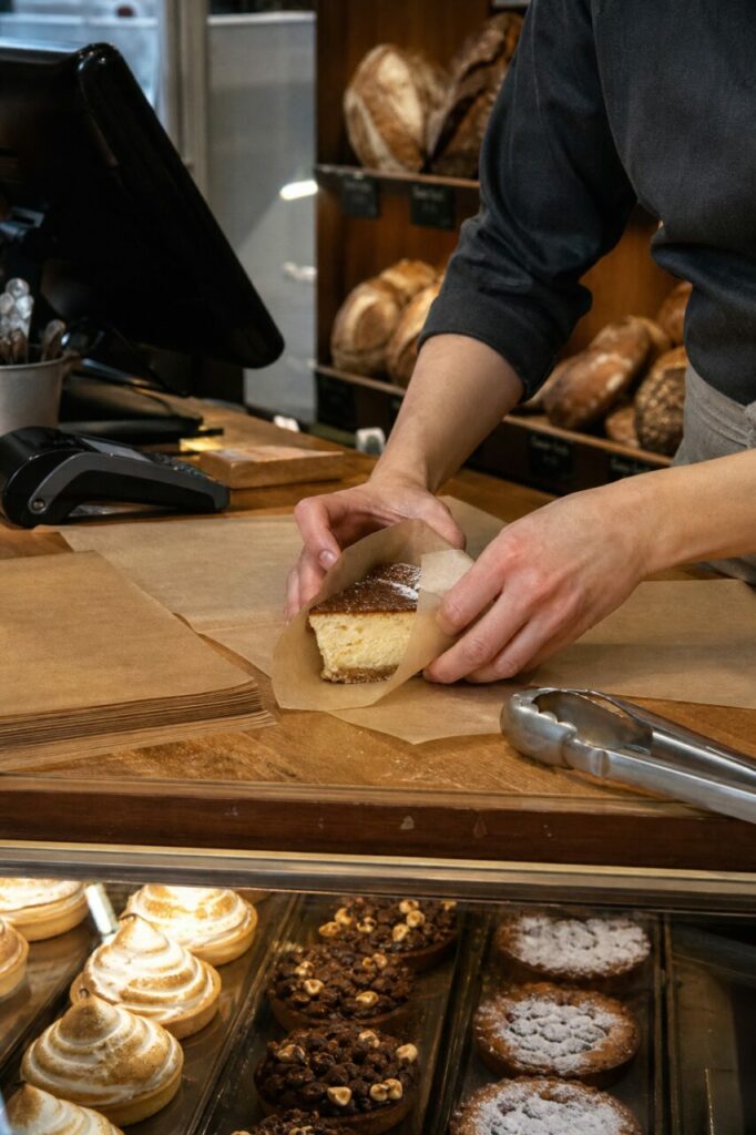 Mains emballant une part de gâteau dans du papier brun