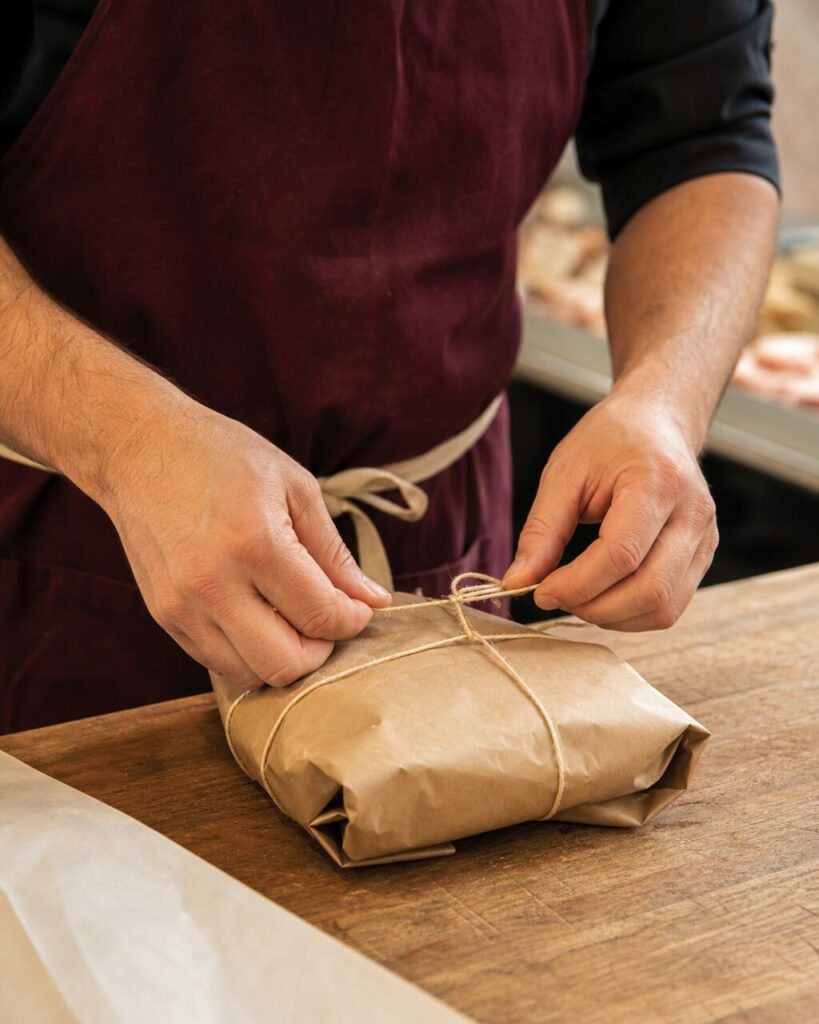 Mains nouant une ficelle autour d’un paquet en papier kraft