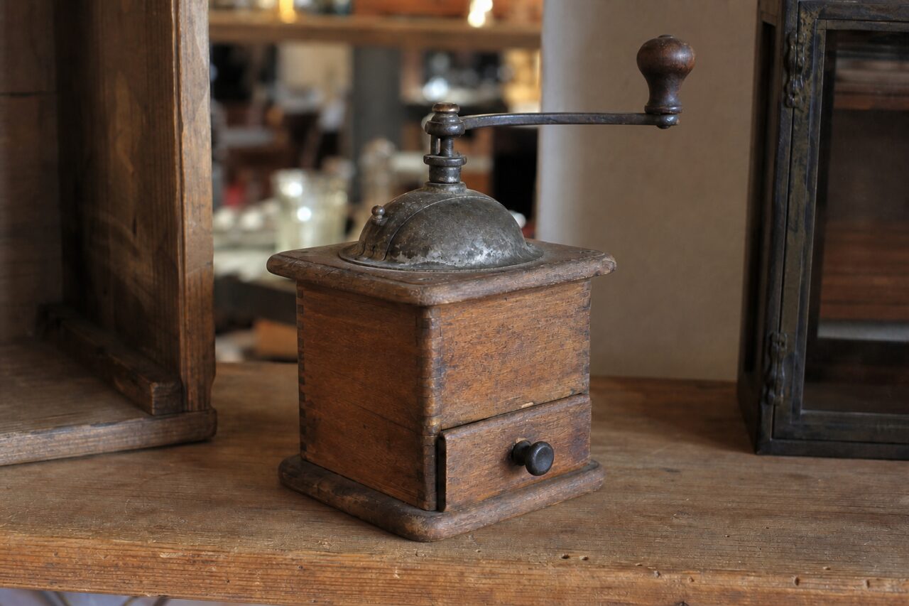 Alte Kaffeemühle aus Holz in Dreiviertelansicht auf einem Regal