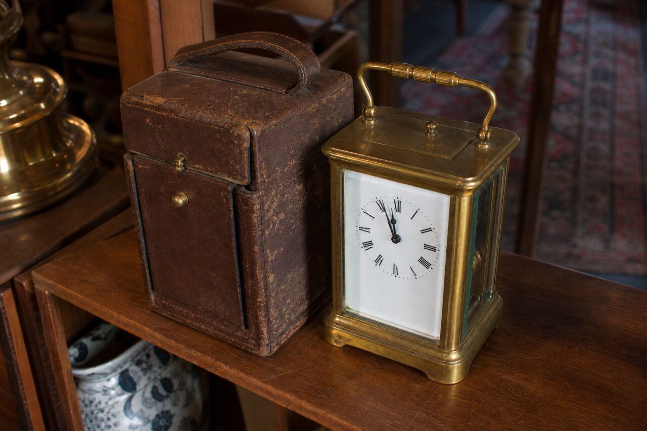 Gilded travel clock seen from a slight overhead angle with its case