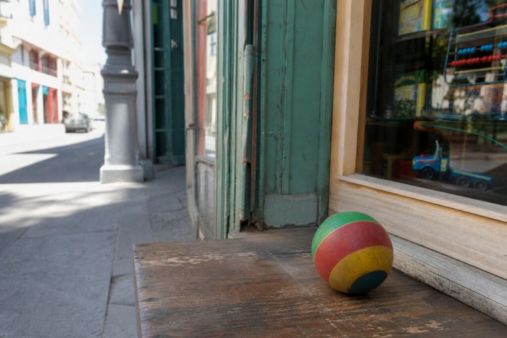 Kleiner gestreifter Ball vor Schaufenster und hellem Gehweg