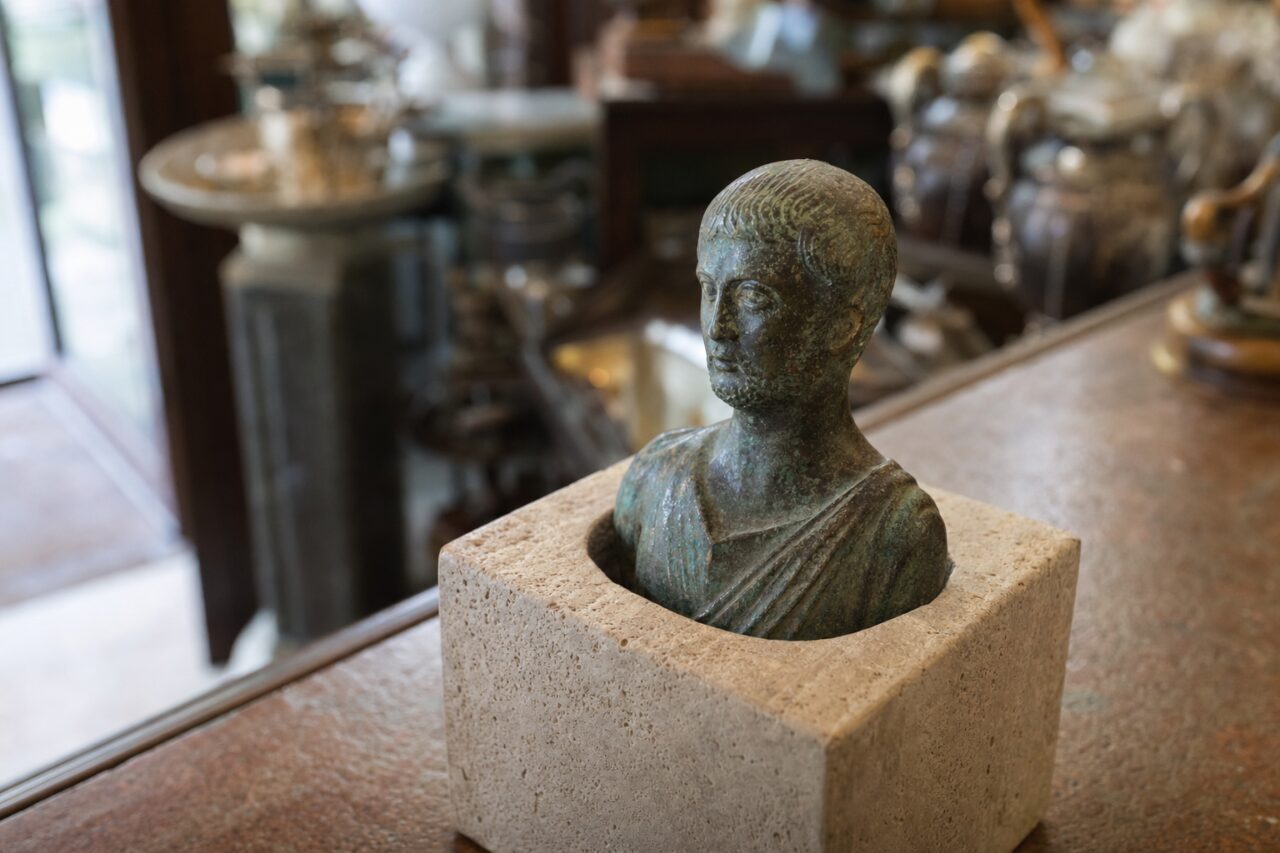 Piccolo busto in metallo patinato inserito in un blocco di pietra chiara